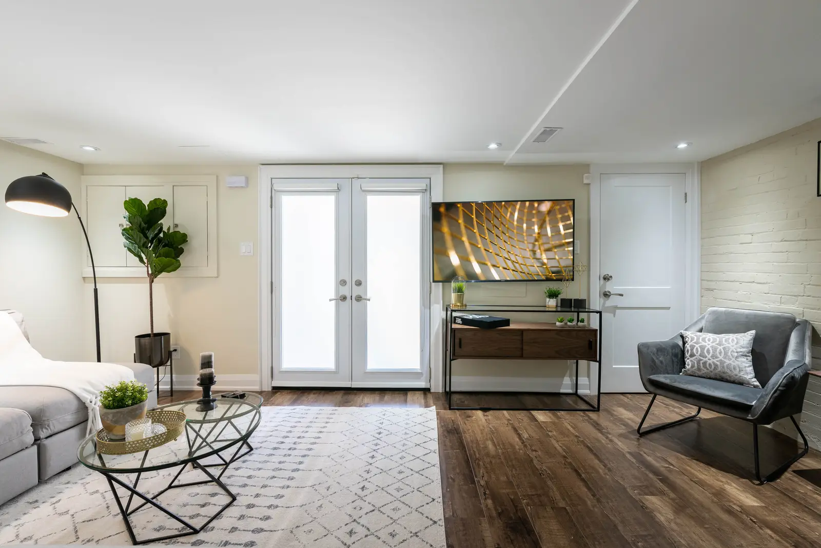 Interior of the house at 309 Manning Avenue in Toronto, with grey chairs, a painted brick wall, and dark wood floors.