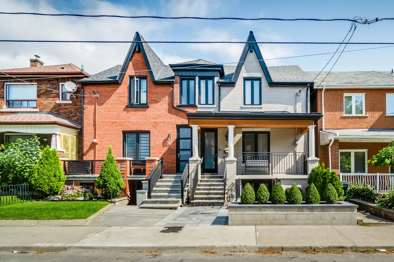 Interior of the house at 309 Manning Avenue in Toronto, with grey chairs, a painted brick wall, and dark wood floors.