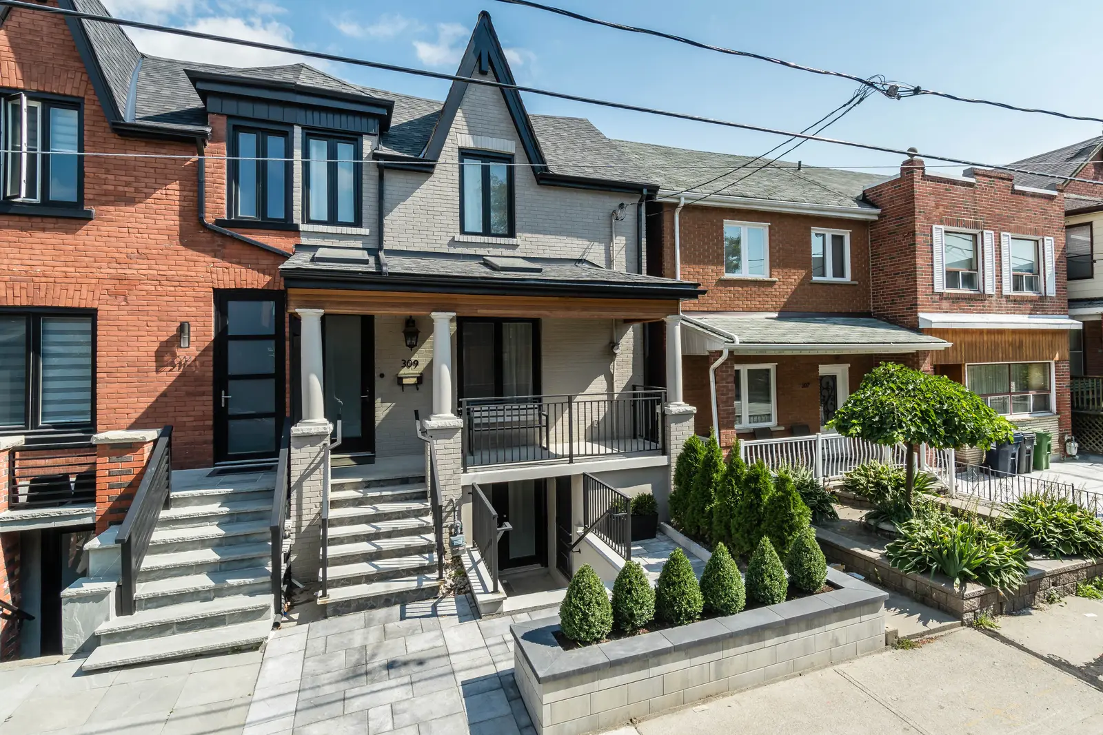 Interior of the house at 309 Manning Avenue in Toronto, with grey chairs, a painted brick wall, and dark wood floors.