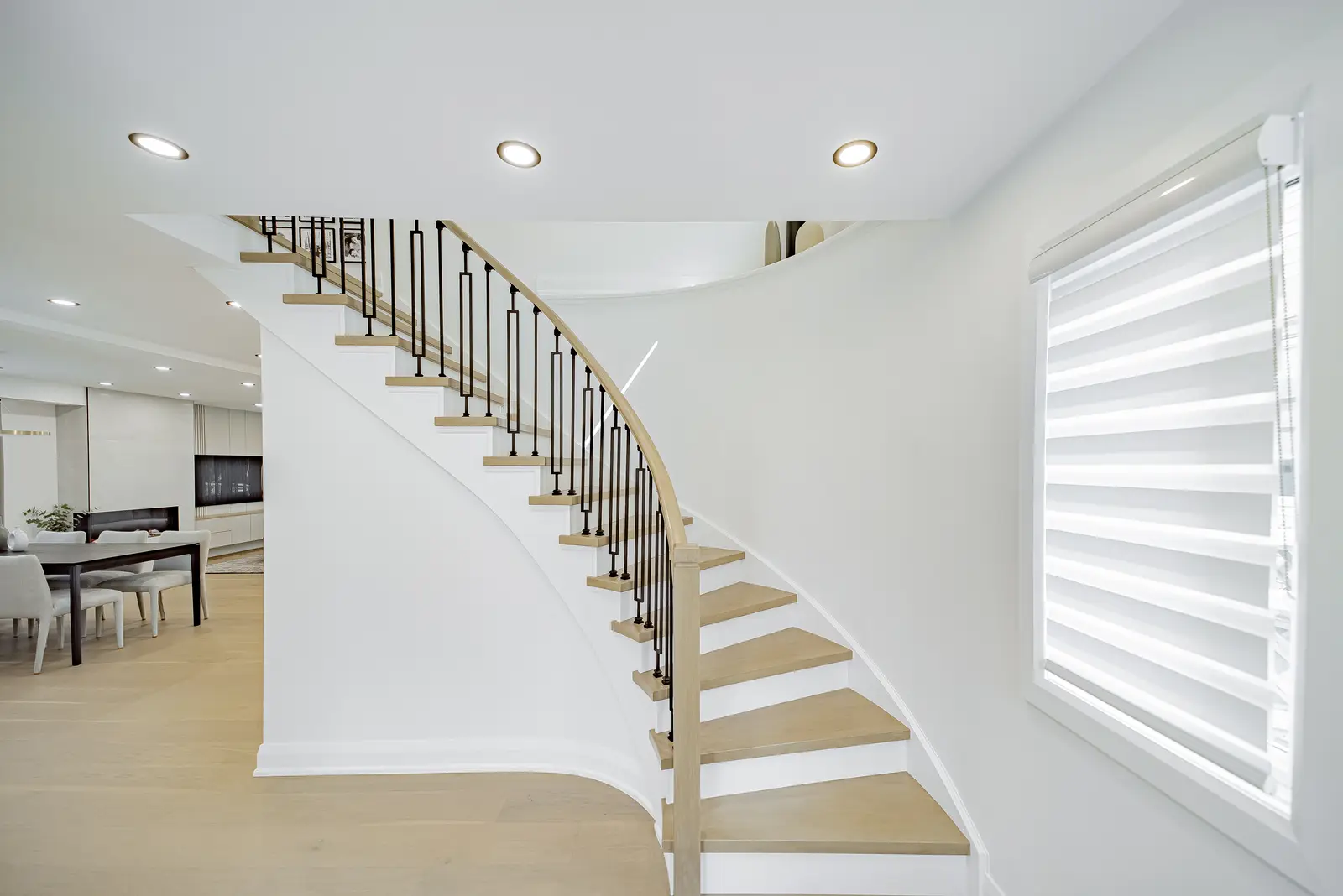 Interior of a Thornhill house renovation, with pale walls, a veined stone kitchen, light wood floors, and black fittings.