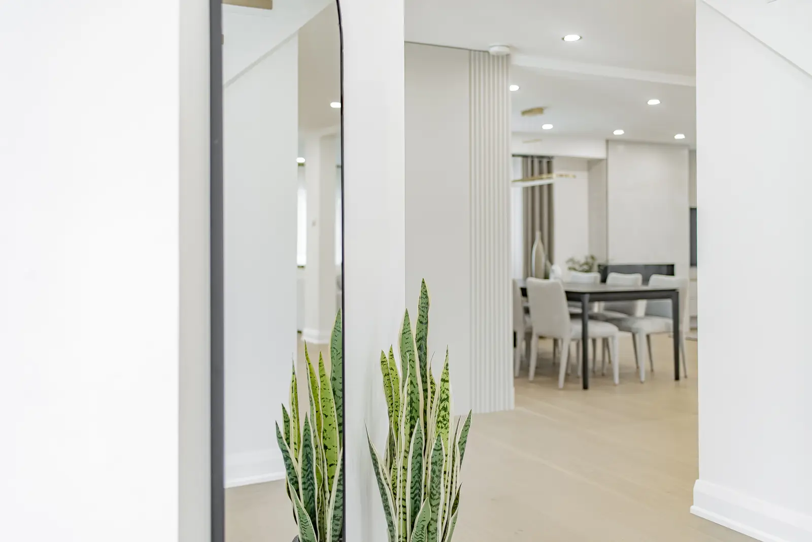 Interior of a Thornhill house renovation, with pale walls, a veined stone kitchen, light wood floors, and black fittings.