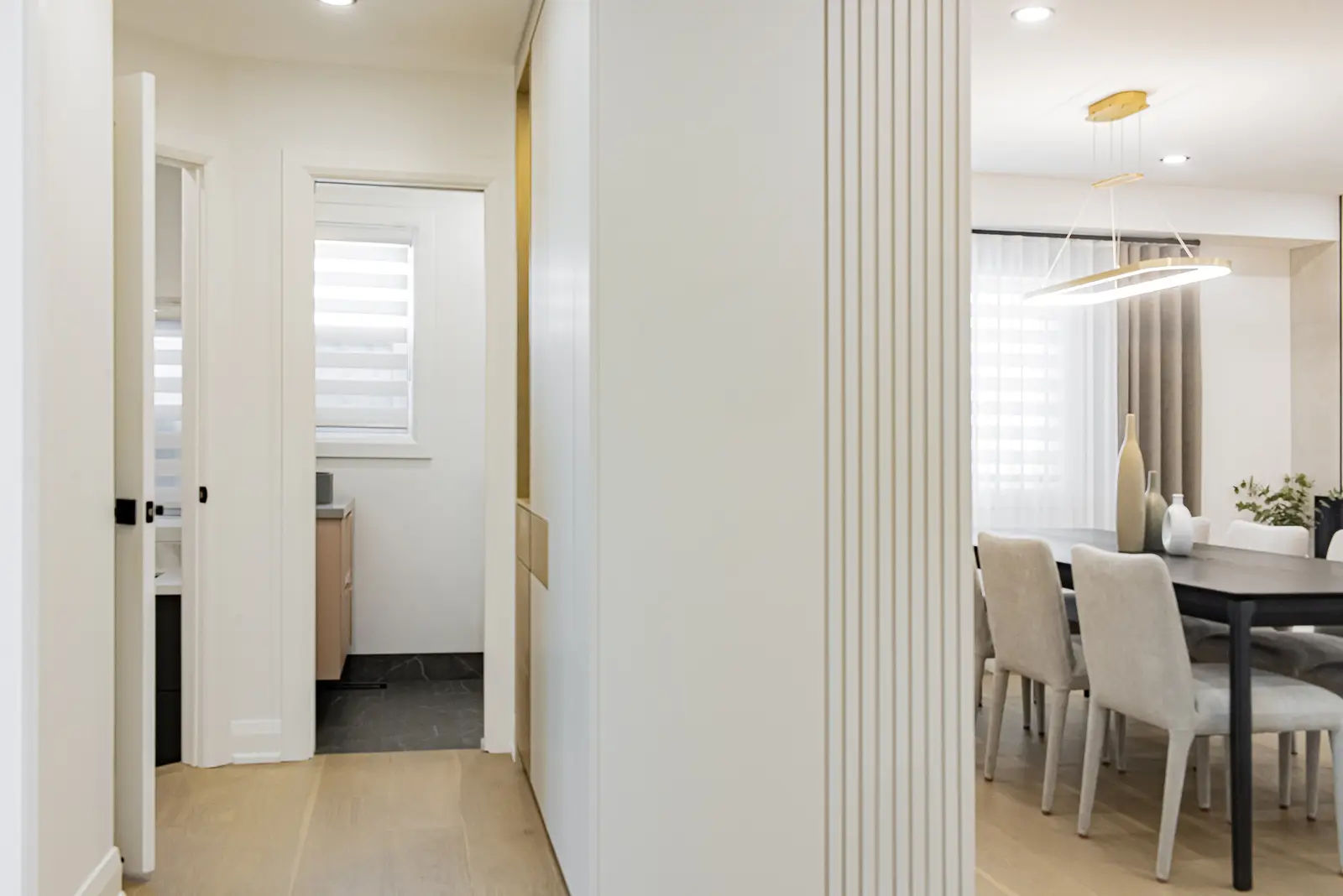 Interior of a Thornhill house renovation, with pale walls, a veined stone kitchen, light wood floors, and black fittings.