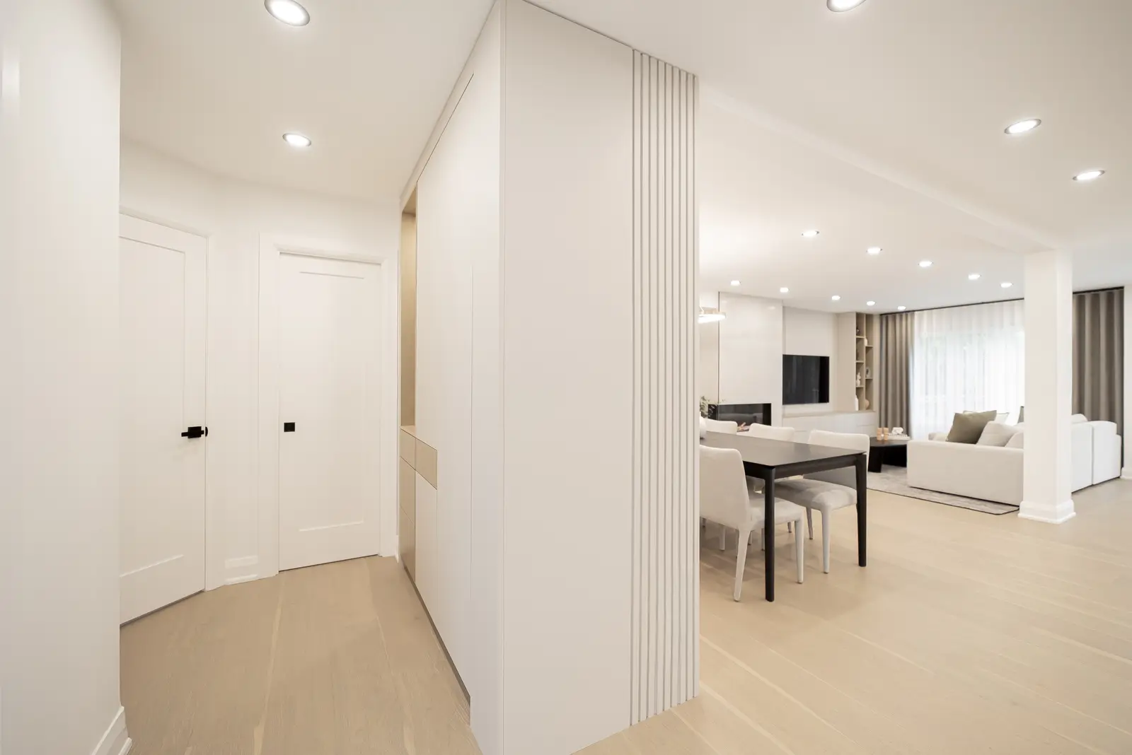 Interior of a Thornhill house renovation, with pale walls, a veined stone kitchen, light wood floors, and black fittings.