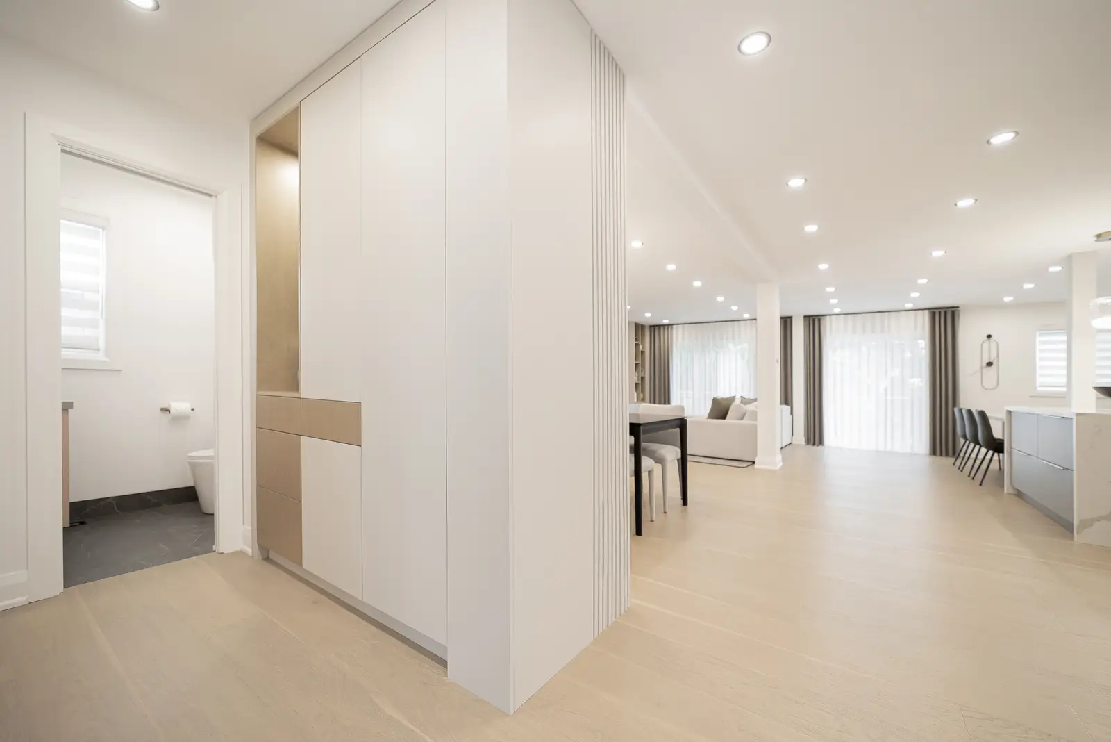 Interior of a Thornhill house renovation, with pale walls, a veined stone kitchen, light wood floors, and black fittings.