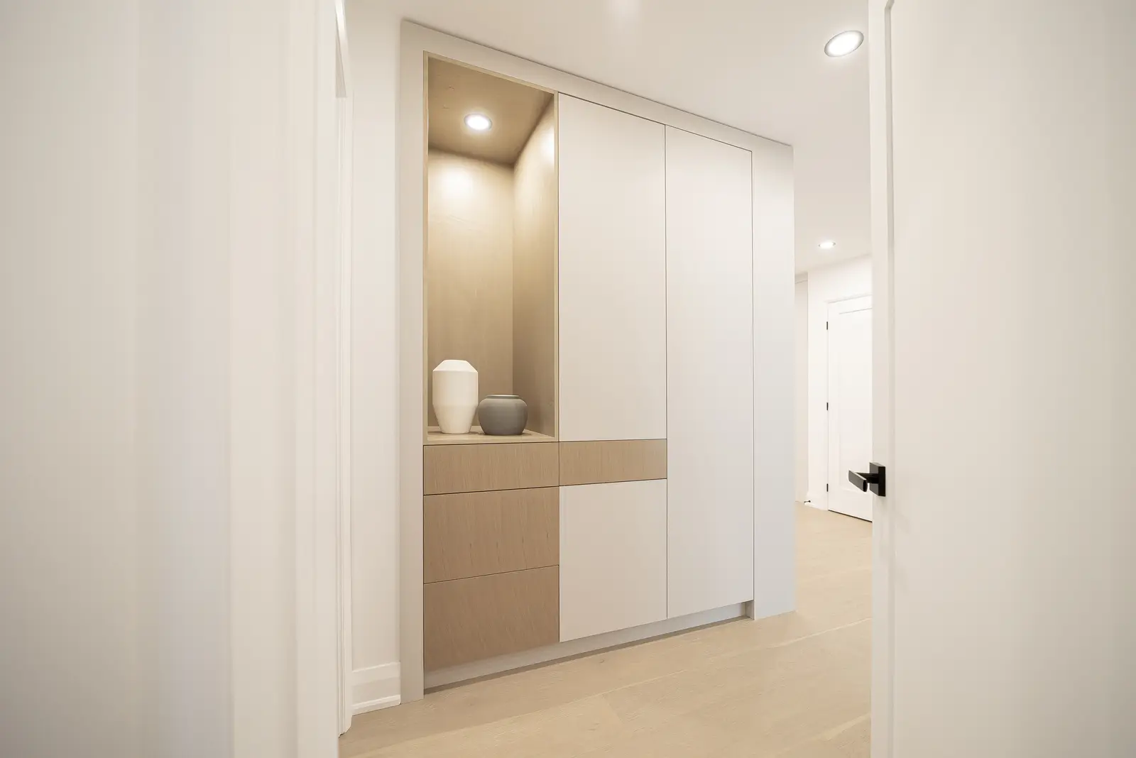 Interior of a Thornhill house renovation, with pale walls, a veined stone kitchen, light wood floors, and black fittings.