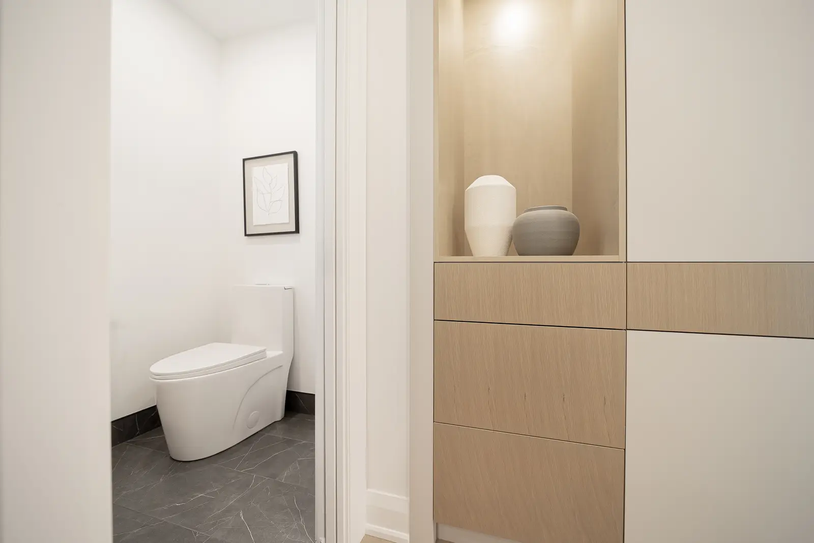 Interior of a Thornhill house renovation, with pale walls, a veined stone kitchen, light wood floors, and black fittings.