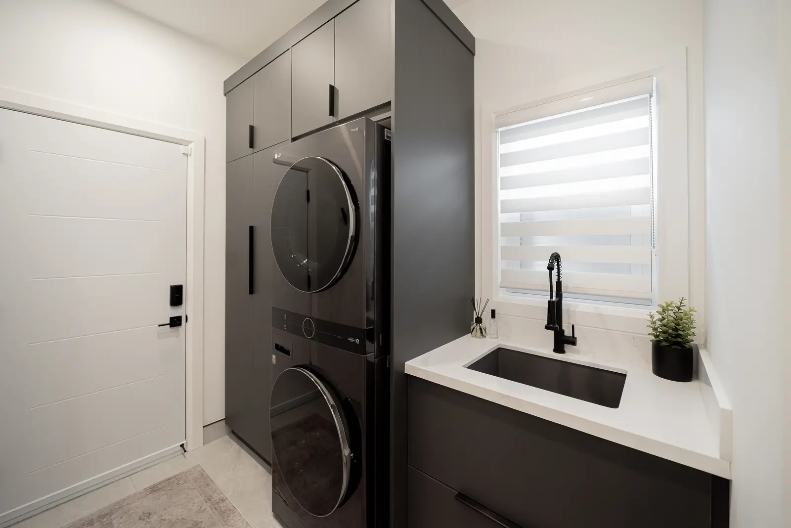 Interior of a Thornhill house renovation, with pale walls, a veined stone kitchen, light wood floors, and black fittings.