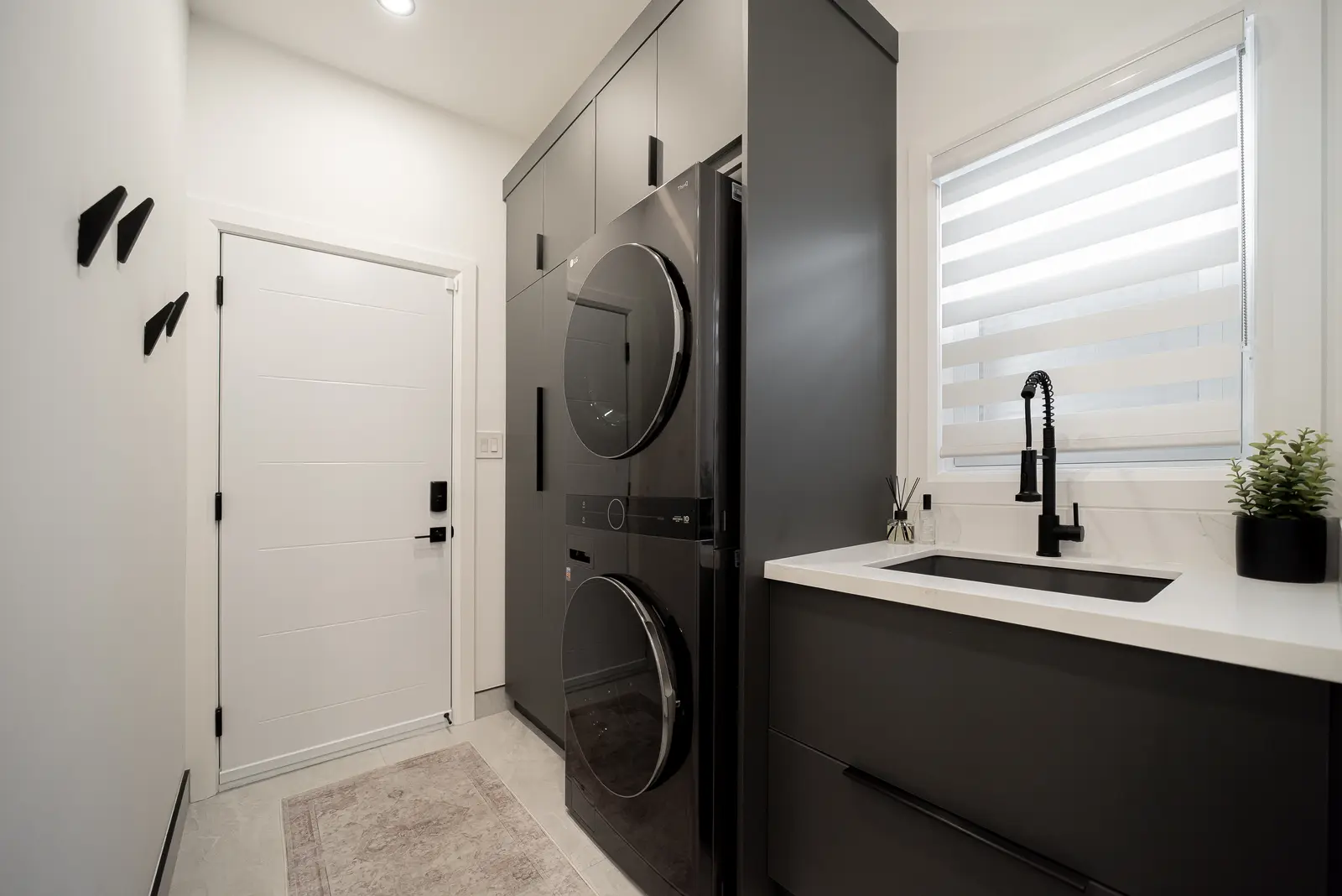 Interior of a Thornhill house renovation, with pale walls, a veined stone kitchen, light wood floors, and black fittings.