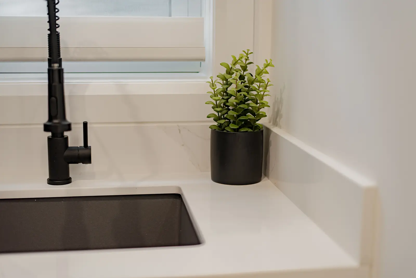 Interior of a Thornhill house renovation, with pale walls, a veined stone kitchen, light wood floors, and black fittings.