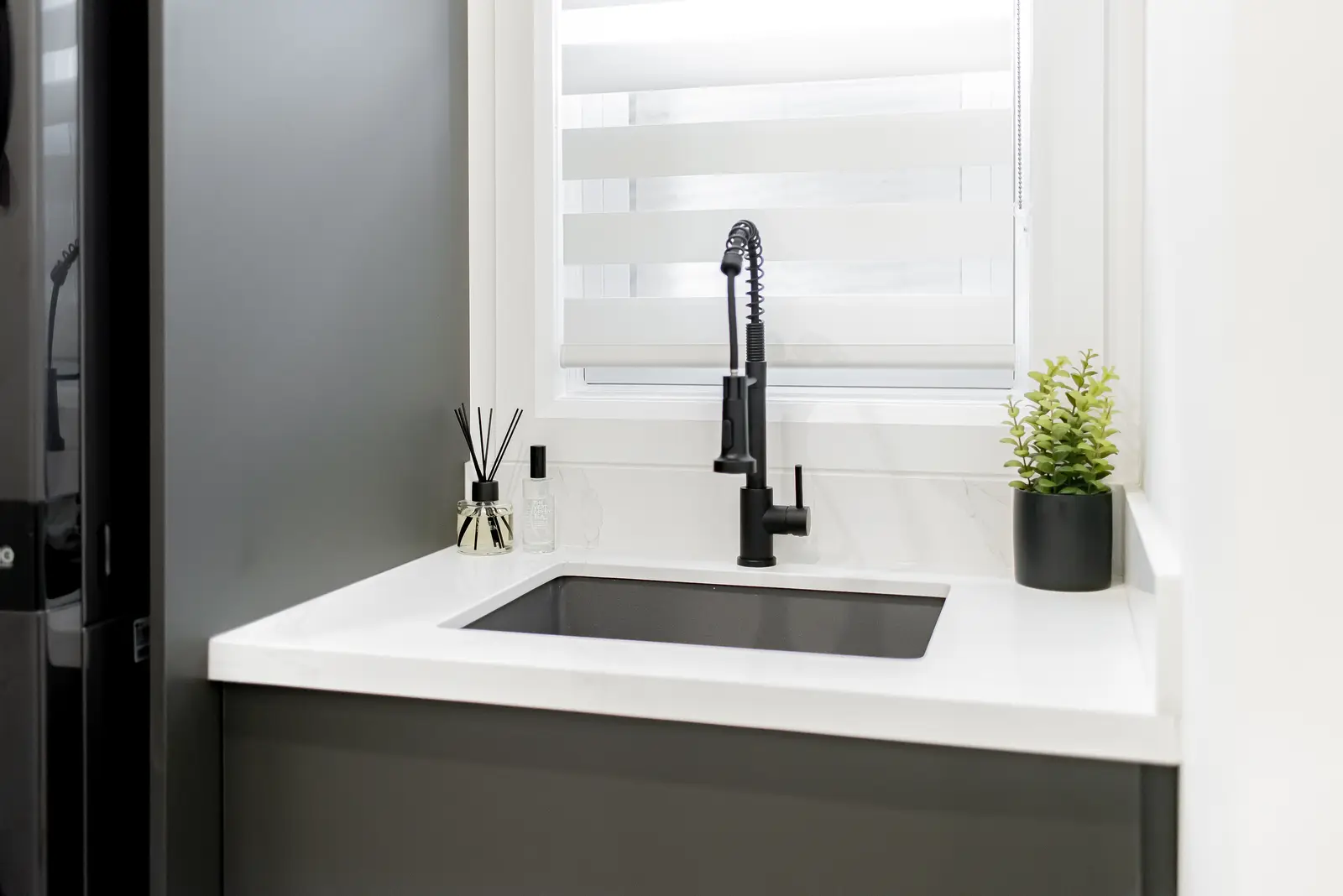 Interior of a Thornhill house renovation, with pale walls, a veined stone kitchen, light wood floors, and black fittings.