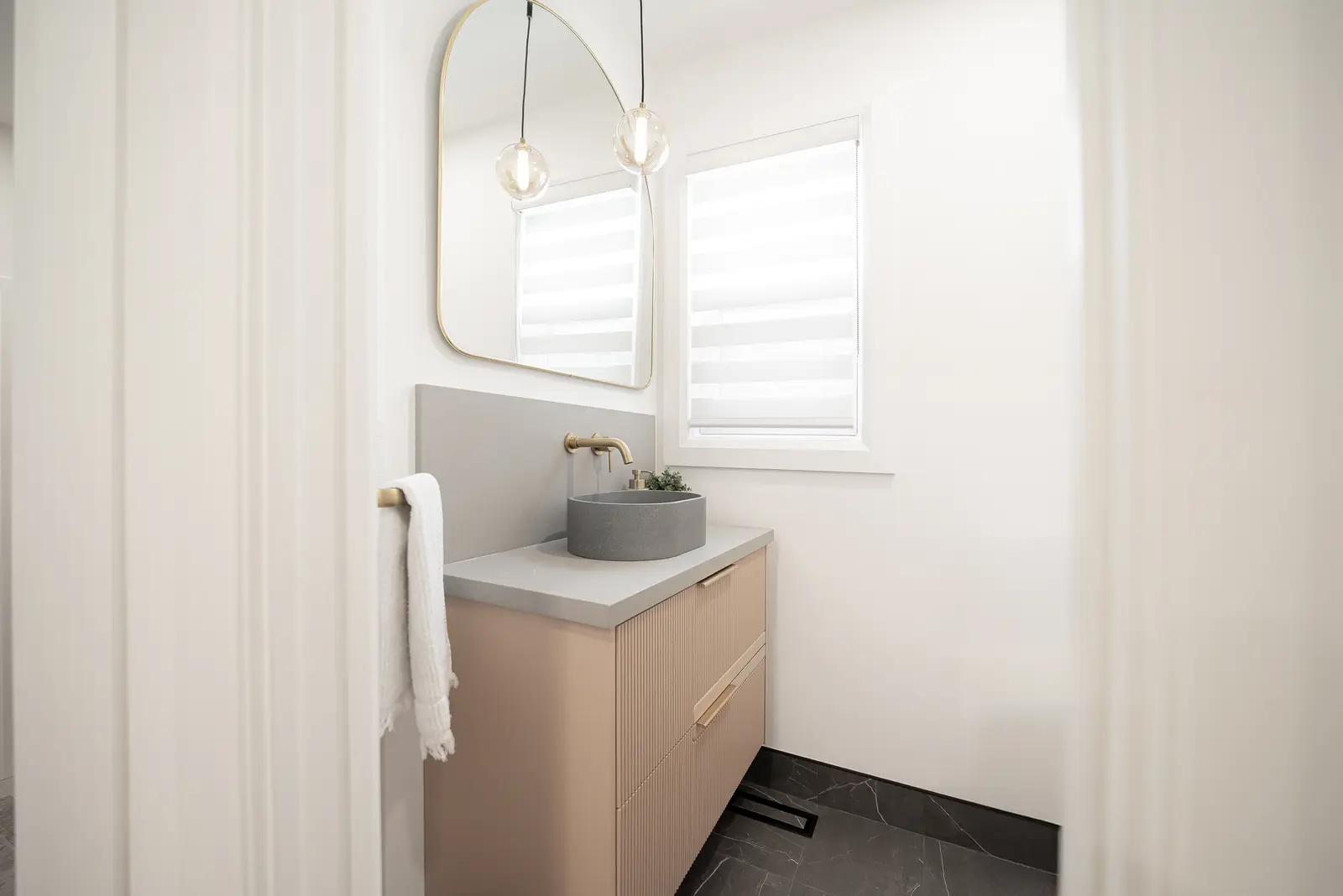 Interior of a Thornhill house renovation, with pale walls, a veined stone kitchen, light wood floors, and black fittings.
