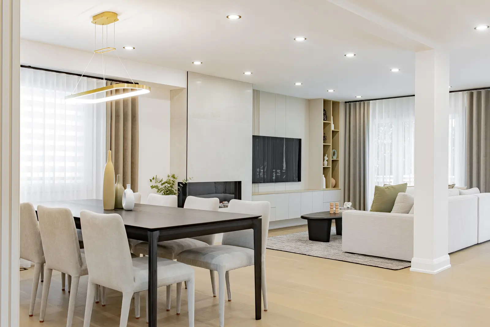 Interior of a Thornhill house renovation, with pale walls, a veined stone kitchen, light wood floors, and black fittings.