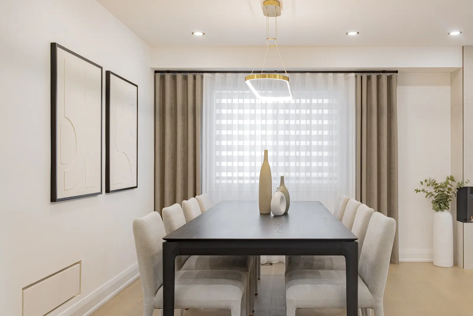 Interior of a Thornhill house renovation, with pale walls, a veined stone kitchen, light wood floors, and black fittings.