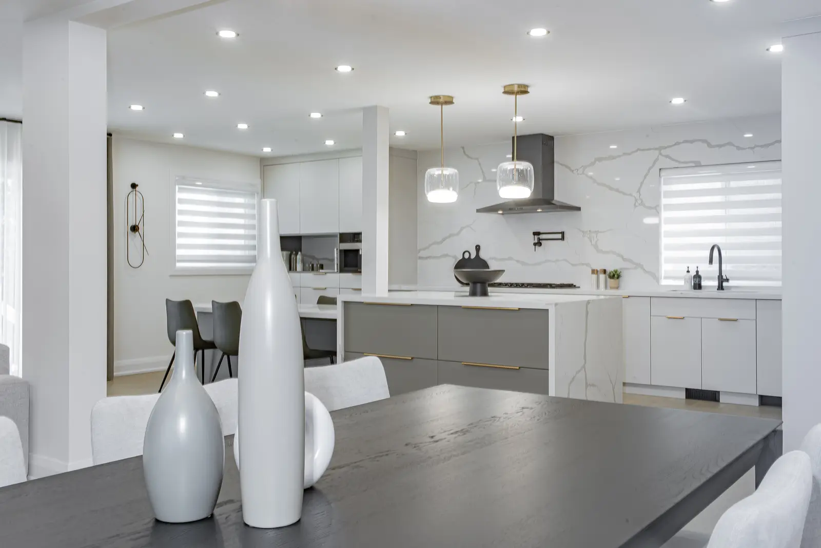 Interior of a Thornhill house renovation, with pale walls, a veined stone kitchen, light wood floors, and black fittings.