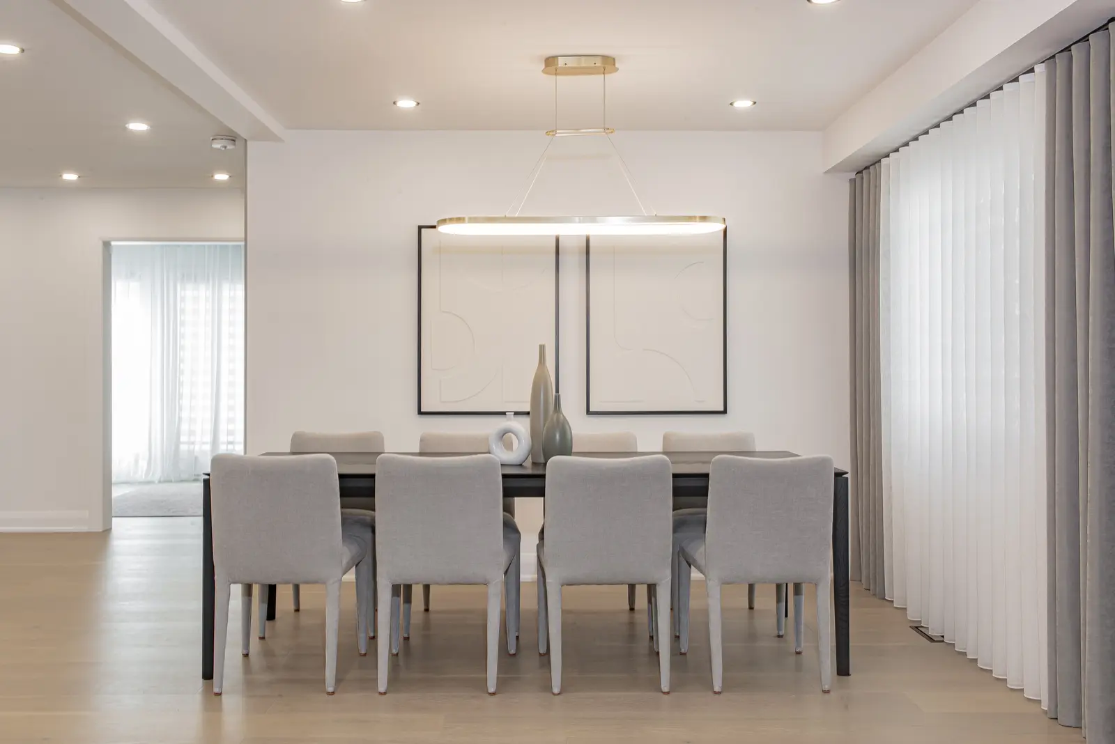 Interior of a Thornhill house renovation, with pale walls, a veined stone kitchen, light wood floors, and black fittings.