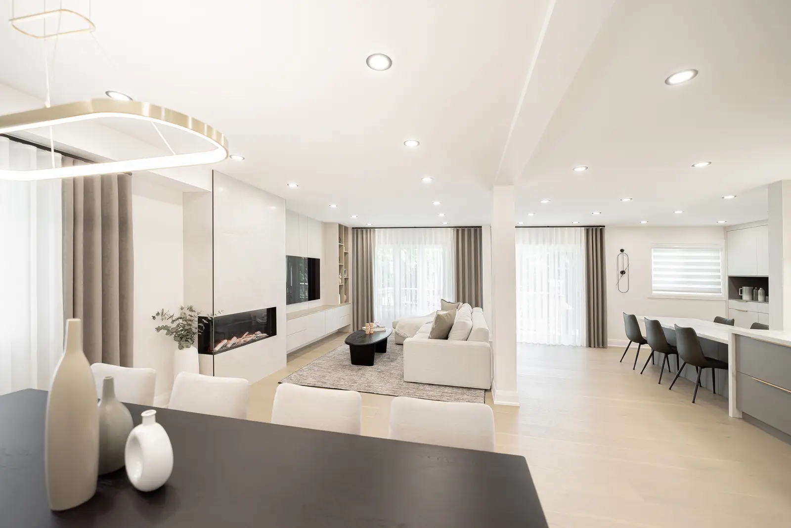 Interior of a Thornhill house renovation, with pale walls, a veined stone kitchen, light wood floors, and black fittings.