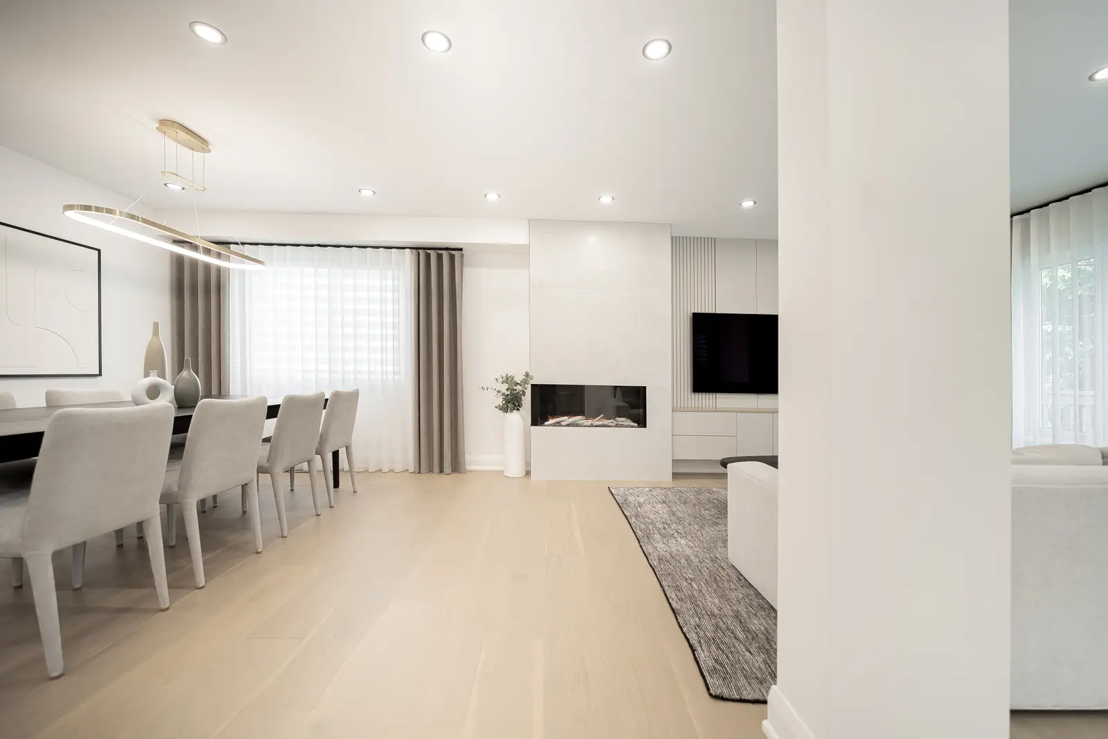 Interior of a Thornhill house renovation, with pale walls, a veined stone kitchen, light wood floors, and black fittings.