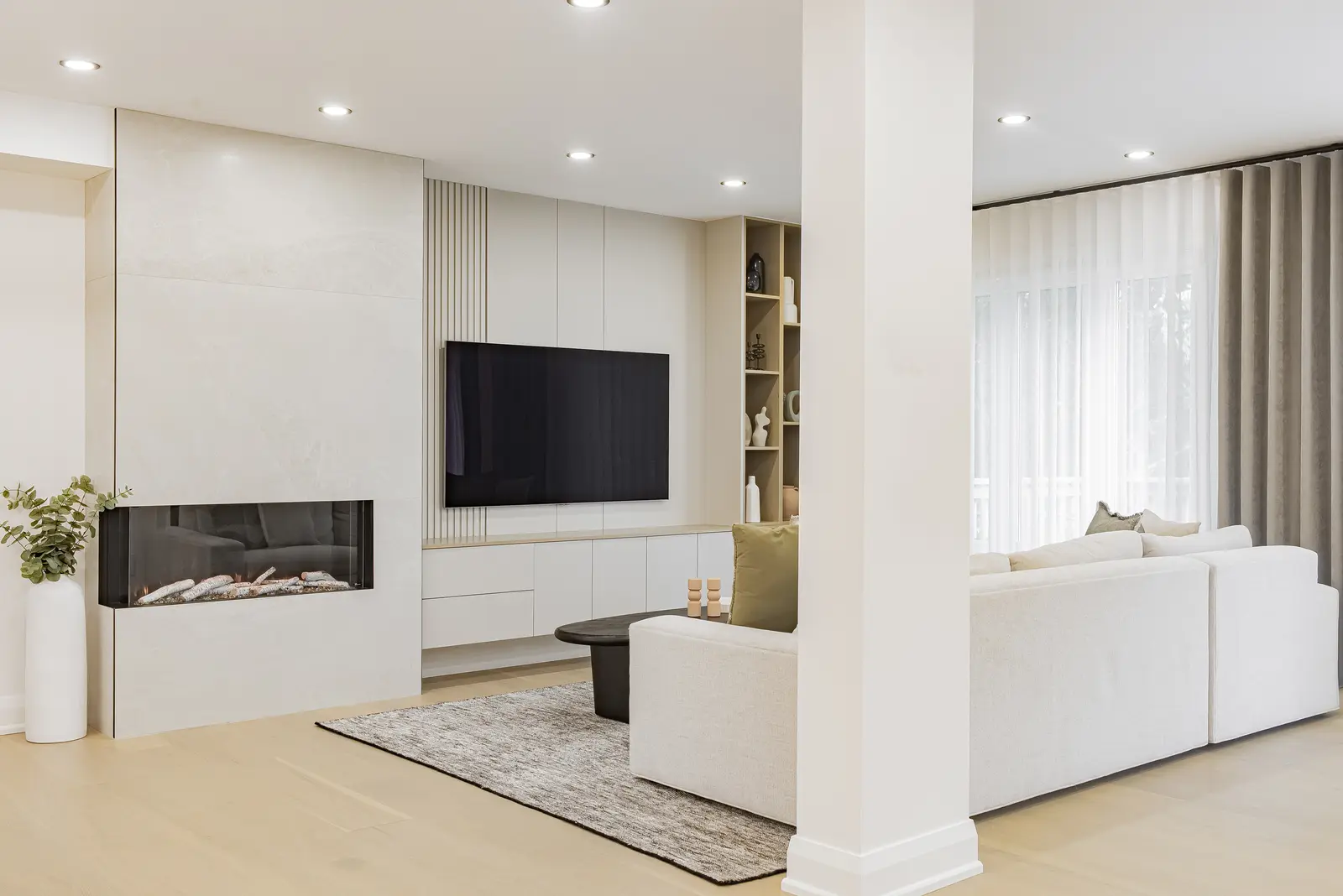 Interior of a Thornhill house renovation, with pale walls, a veined stone kitchen, light wood floors, and black fittings.