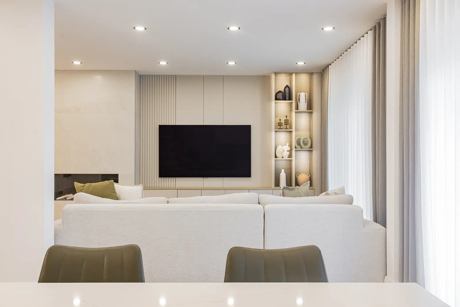 Interior of a Thornhill house renovation, with pale walls, a veined stone kitchen, light wood floors, and black fittings.