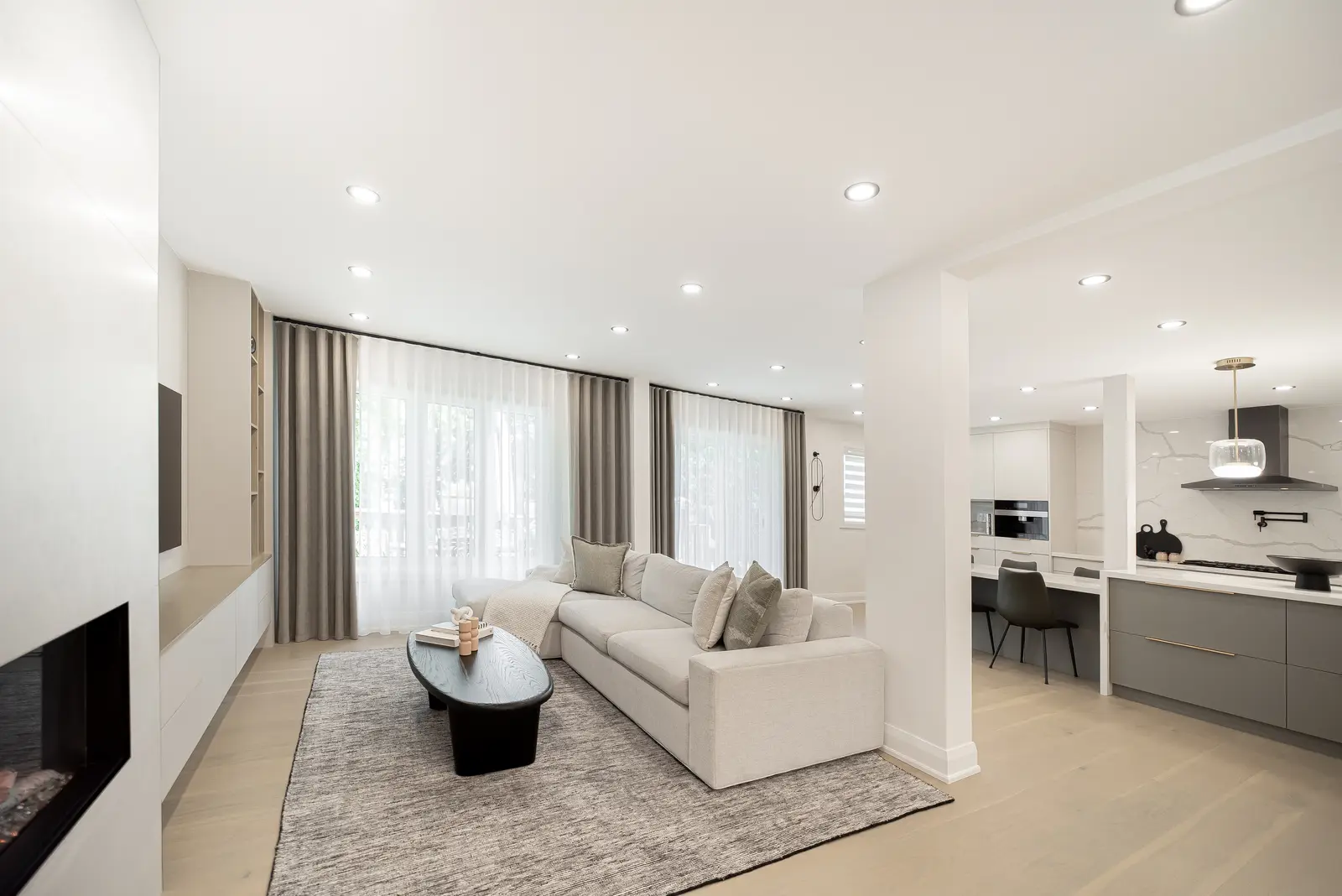 Interior of a Thornhill house renovation, with pale walls, a veined stone kitchen, light wood floors, and black fittings.