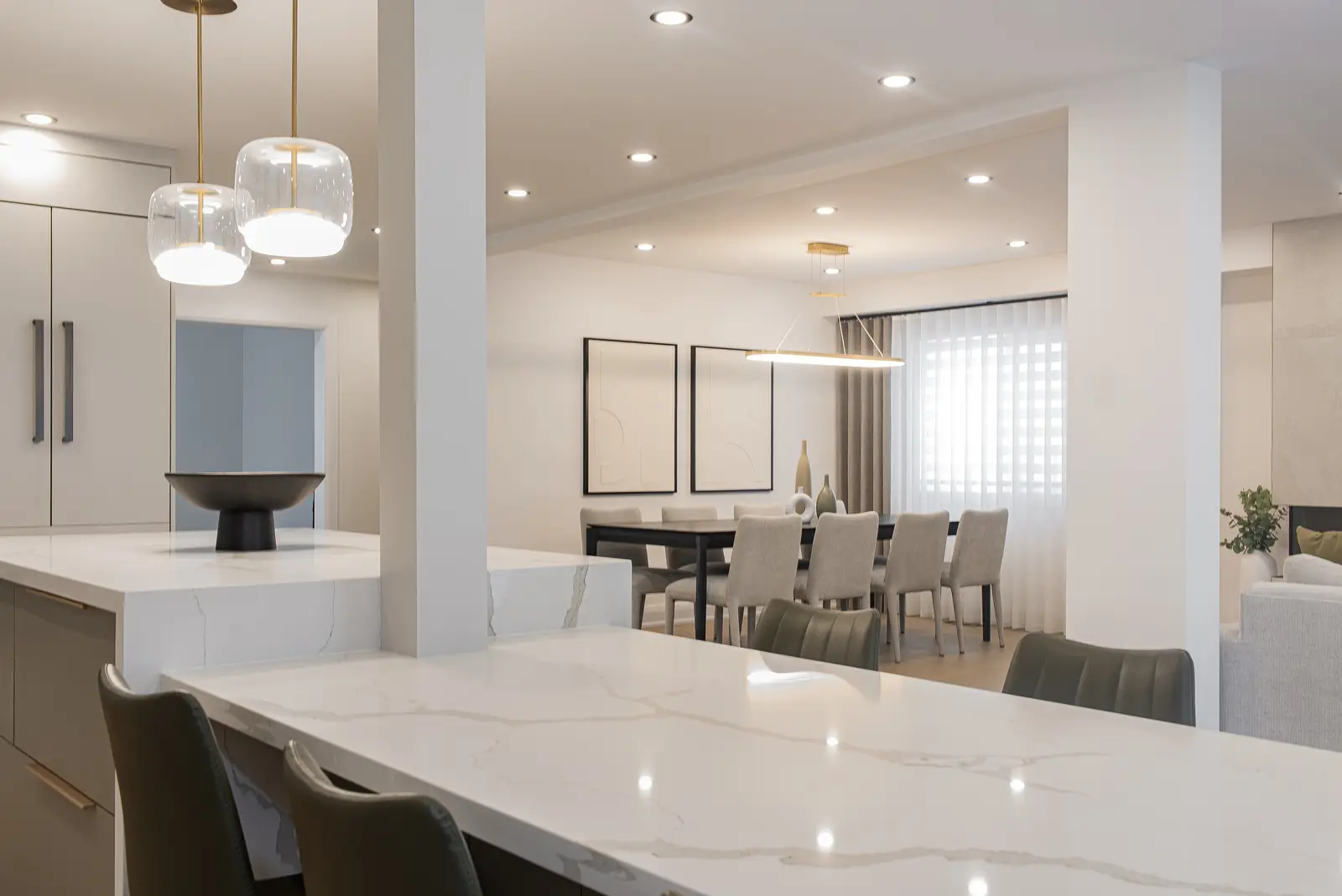 Interior of a Thornhill house renovation, with pale walls, a veined stone kitchen, light wood floors, and black fittings.