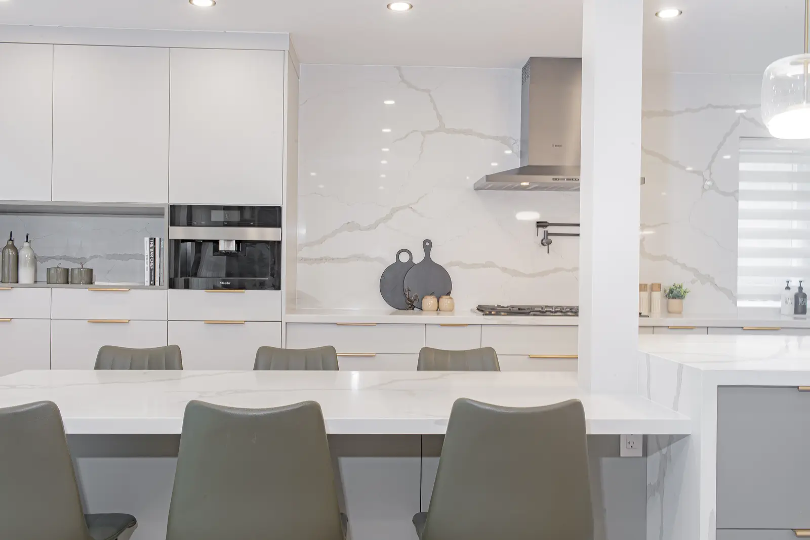 Interior of a Thornhill house renovation, with pale walls, a veined stone kitchen, light wood floors, and black fittings.