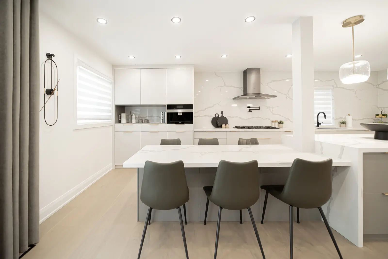Interior of a Thornhill house renovation, with pale walls, a veined stone kitchen, light wood floors, and black fittings.