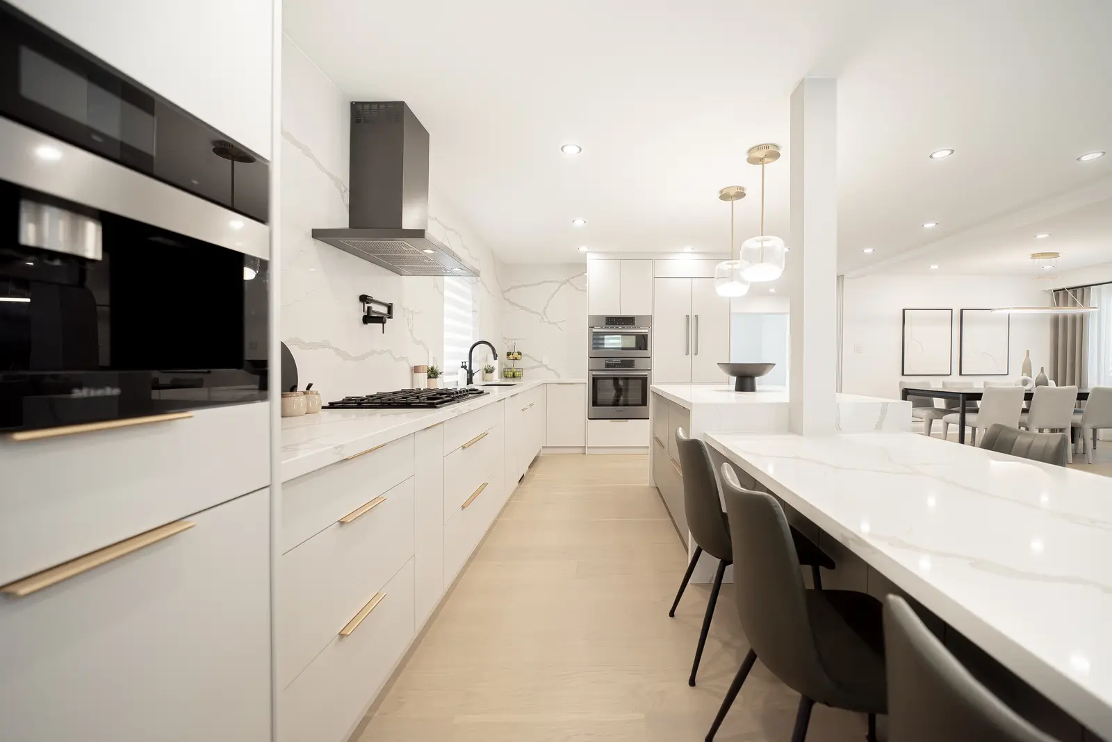 Interior of a Thornhill house renovation, with pale walls, a veined stone kitchen, light wood floors, and black fittings.
