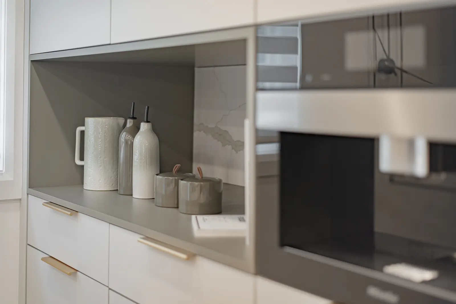 Interior of a Thornhill house renovation, with pale walls, a veined stone kitchen, light wood floors, and black fittings.