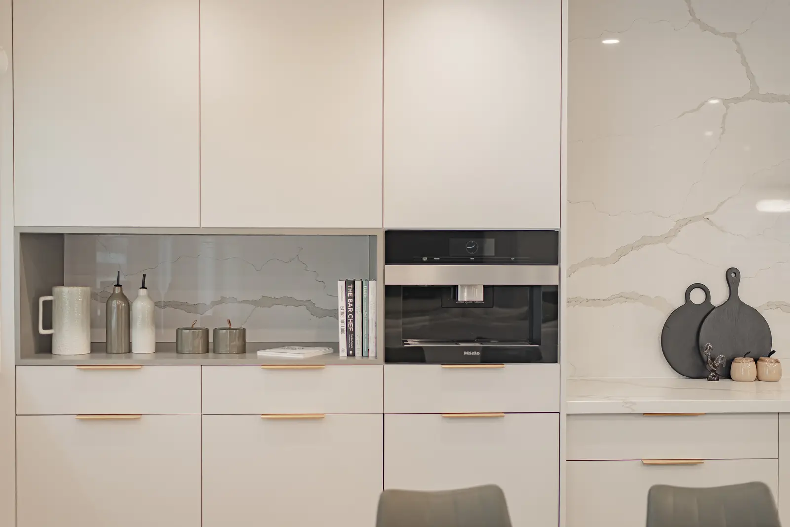 Interior of a Thornhill house renovation, with pale walls, a veined stone kitchen, light wood floors, and black fittings.