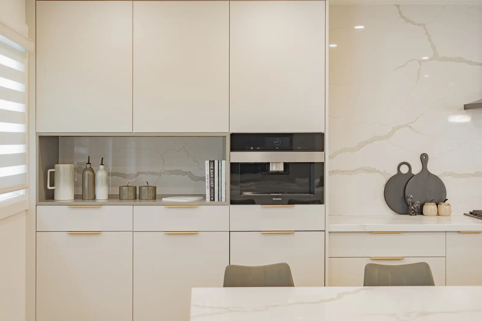 Interior of a Thornhill house renovation, with pale walls, a veined stone kitchen, light wood floors, and black fittings.