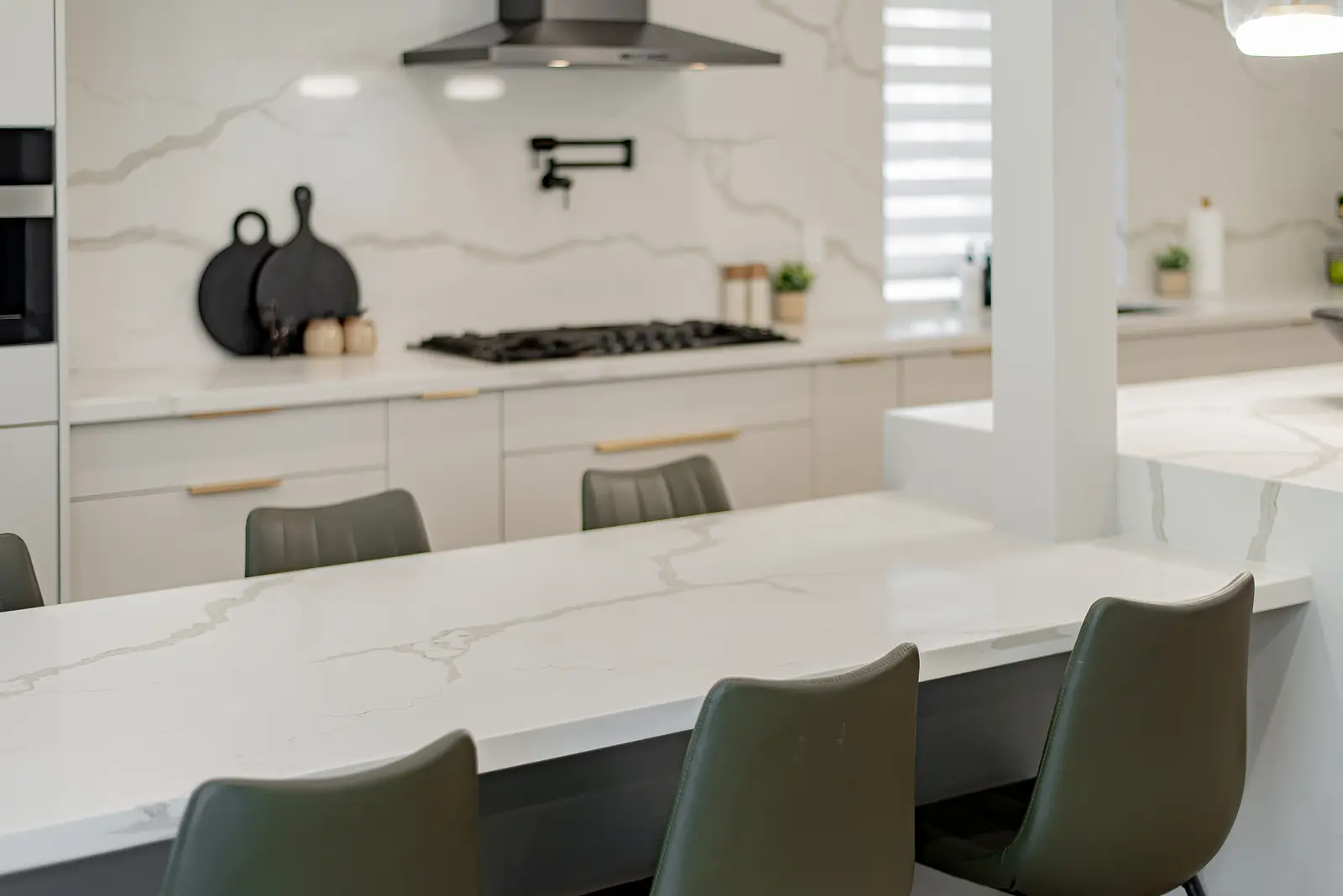 Interior of a Thornhill house renovation, with pale walls, a veined stone kitchen, light wood floors, and black fittings.