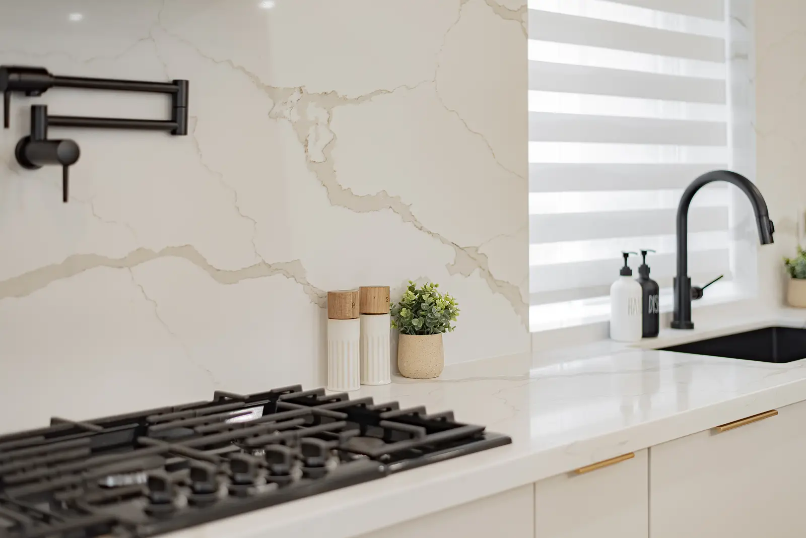 Interior of a Thornhill house renovation, with pale walls, a veined stone kitchen, light wood floors, and black fittings.