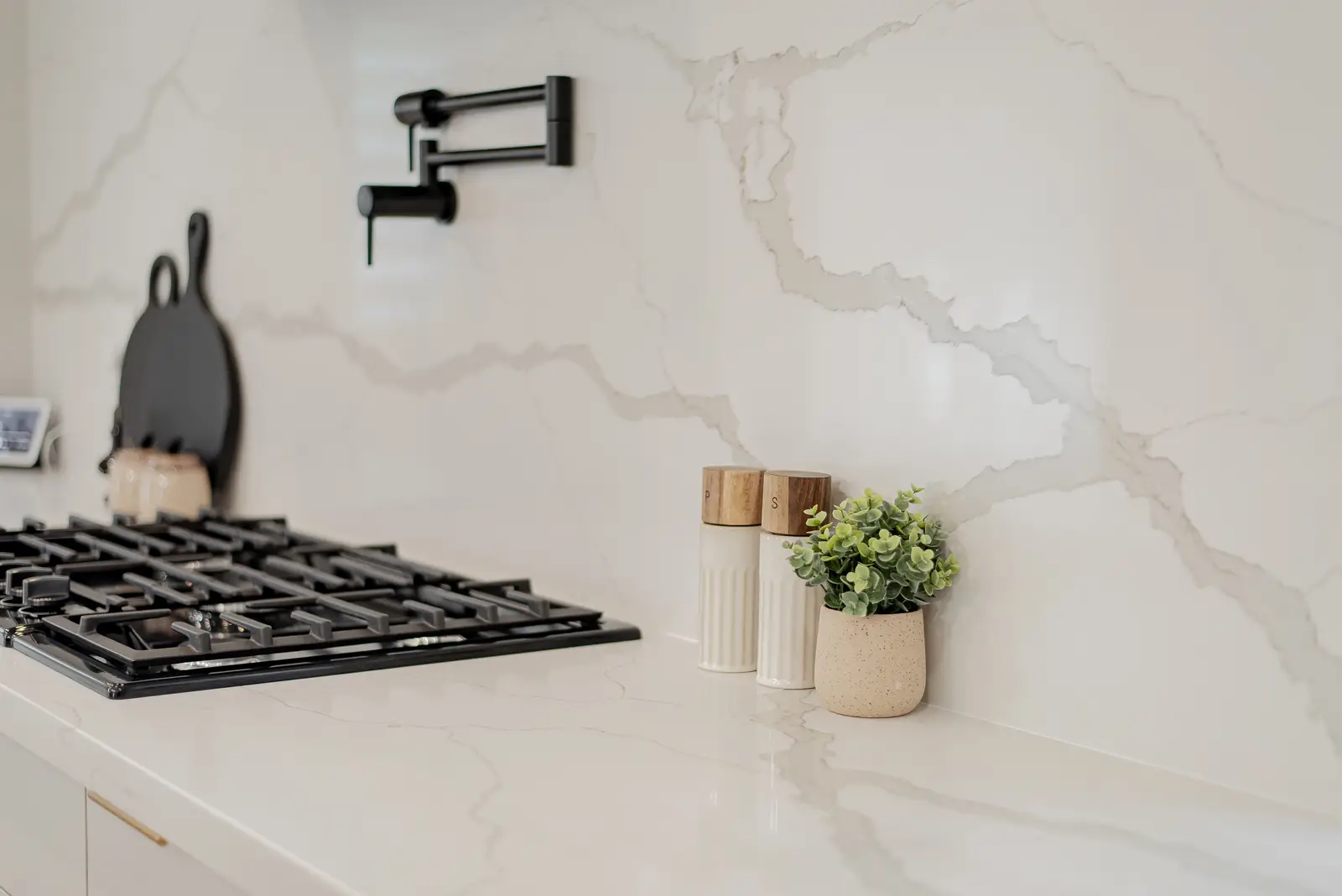 Interior of a Thornhill house renovation, with pale walls, a veined stone kitchen, light wood floors, and black fittings.