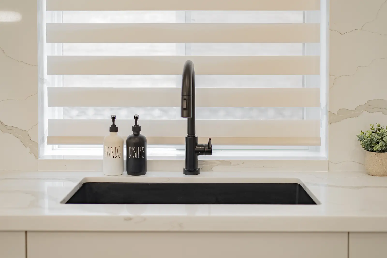 Interior of a Thornhill house renovation, with pale walls, a veined stone kitchen, light wood floors, and black fittings.