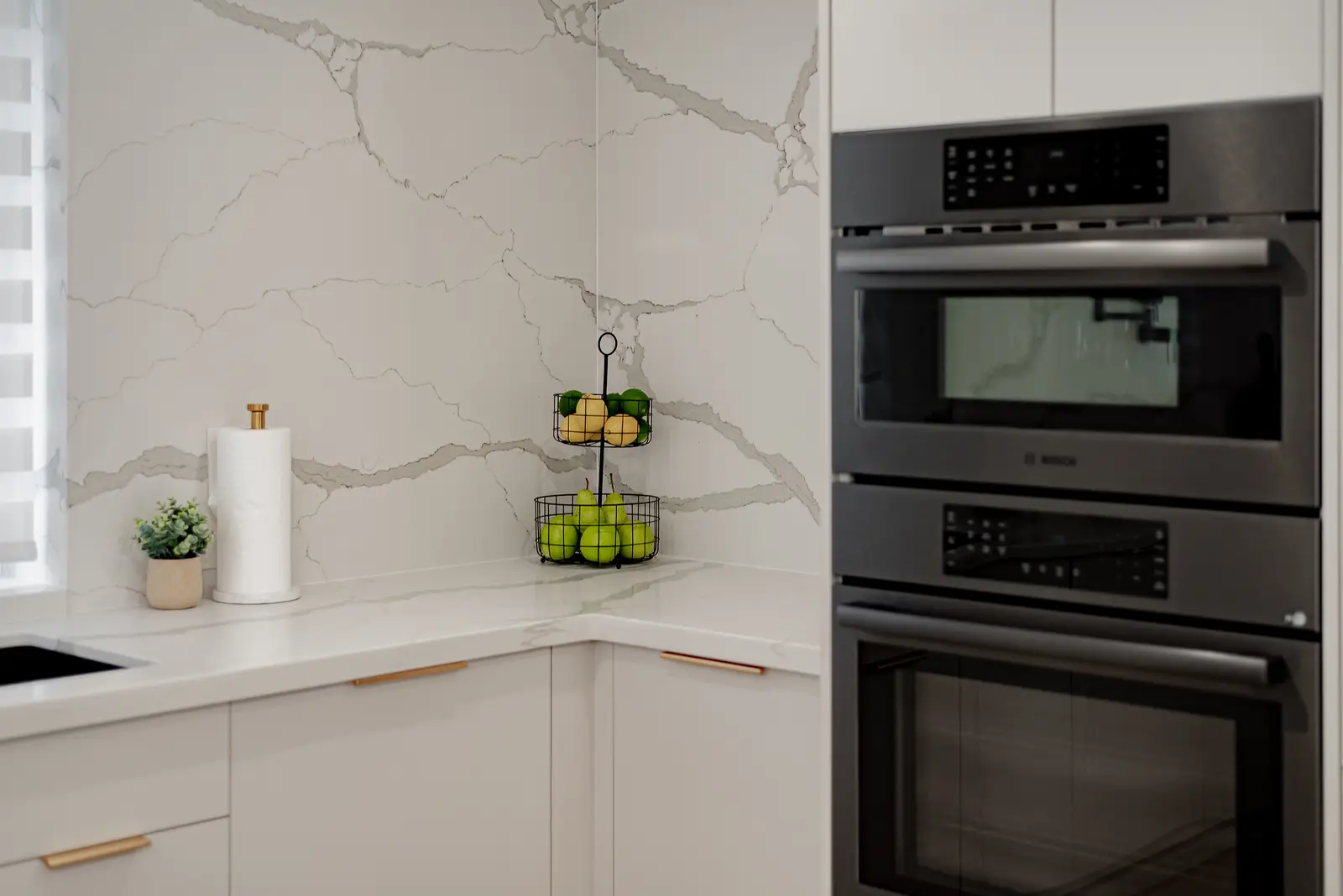 Interior of a Thornhill house renovation, with pale walls, a veined stone kitchen, light wood floors, and black fittings.