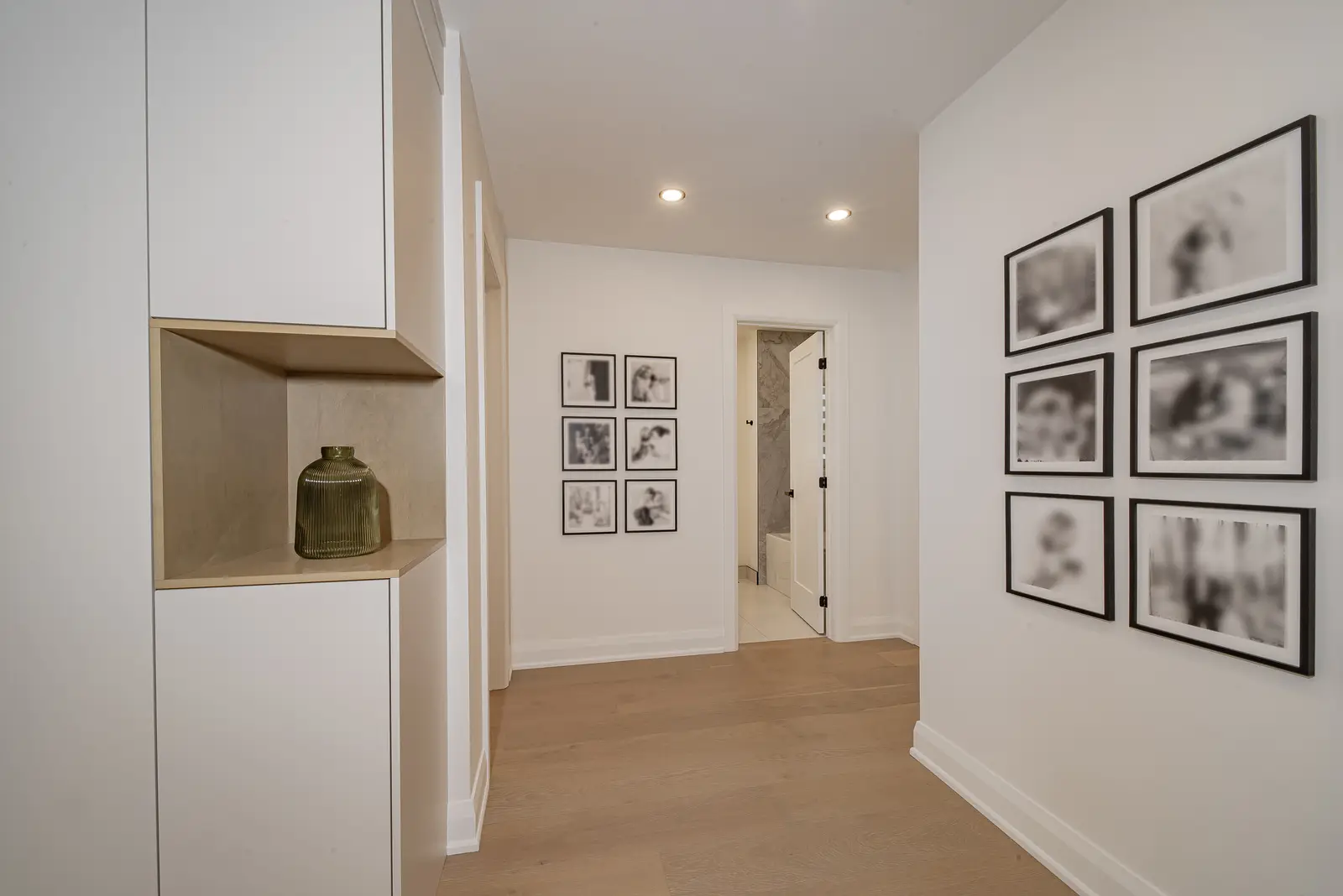 Interior of a Thornhill house renovation, with pale walls, a veined stone kitchen, light wood floors, and black fittings.