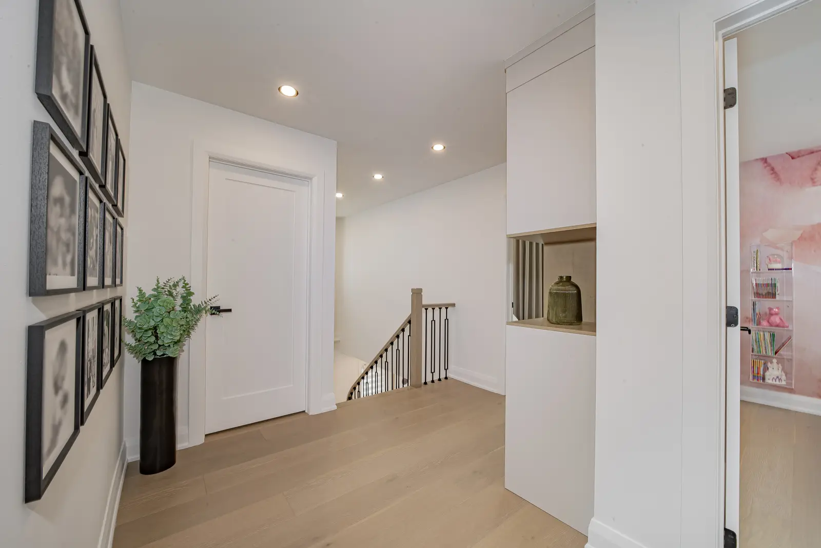 Interior of a Thornhill house renovation, with pale walls, a veined stone kitchen, light wood floors, and black fittings.