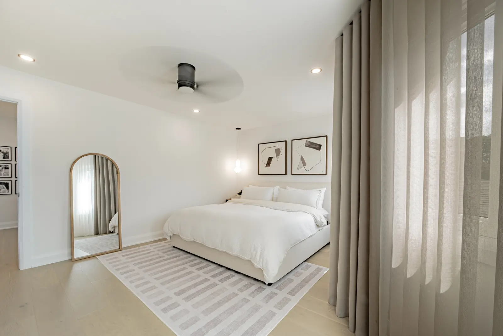 Interior of a Thornhill house renovation, with pale walls, a veined stone kitchen, light wood floors, and black fittings.