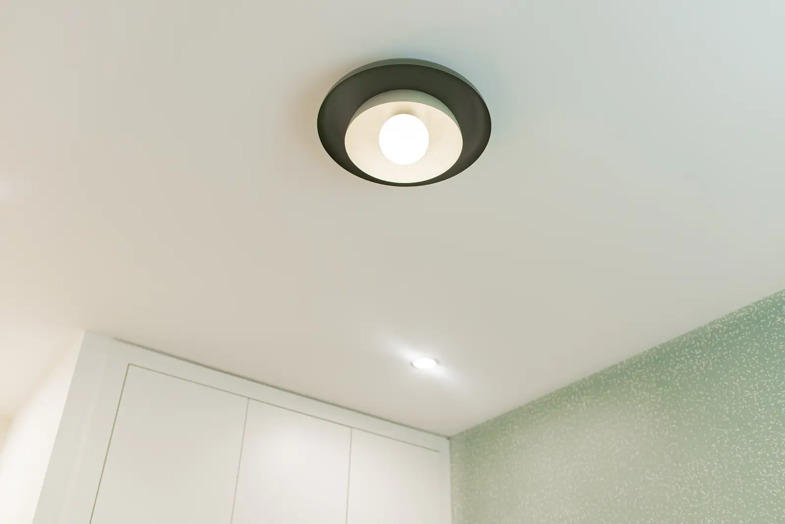 Interior of a Thornhill house renovation, with pale walls, a veined stone kitchen, light wood floors, and black fittings.