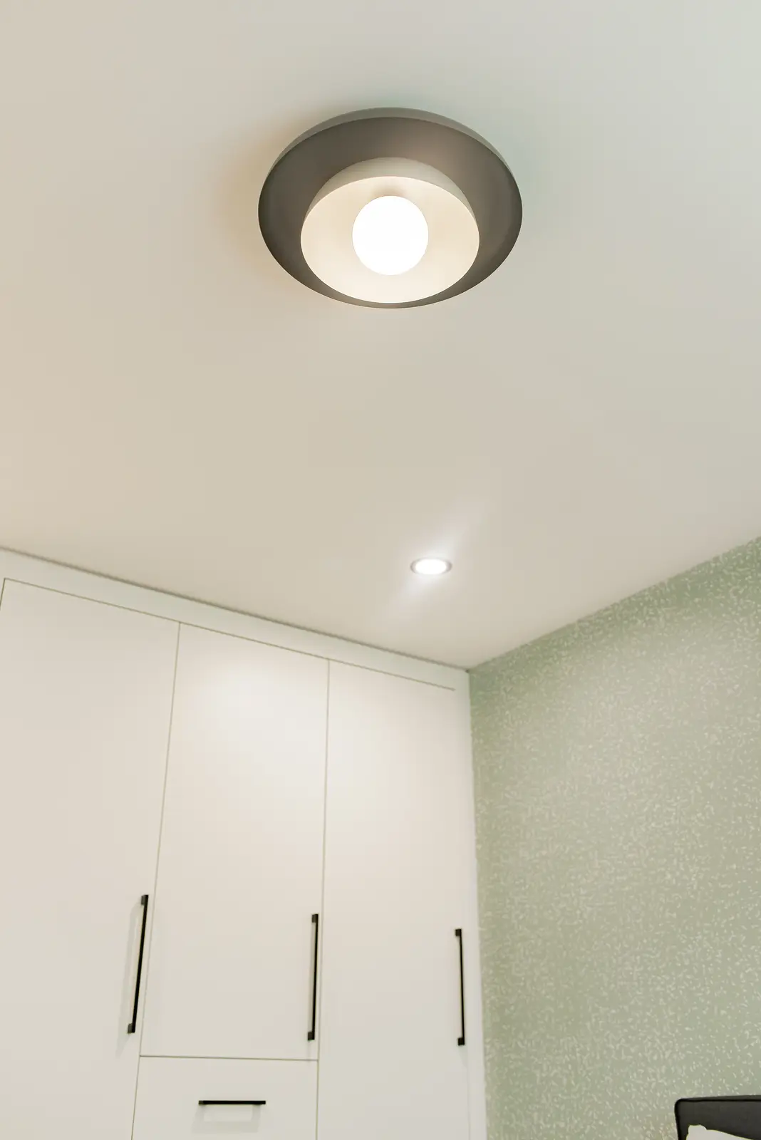 Interior of a Thornhill house renovation, with pale walls, a veined stone kitchen, light wood floors, and black fittings.