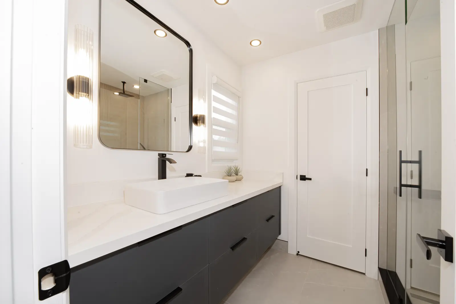 Interior of a Thornhill house renovation, with pale walls, a veined stone kitchen, light wood floors, and black fittings.
