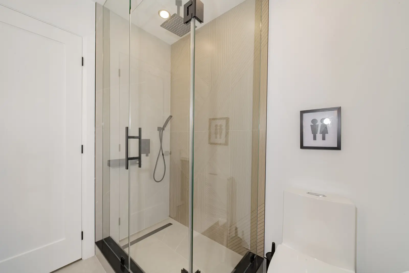 Interior of a Thornhill house renovation, with pale walls, a veined stone kitchen, light wood floors, and black fittings.