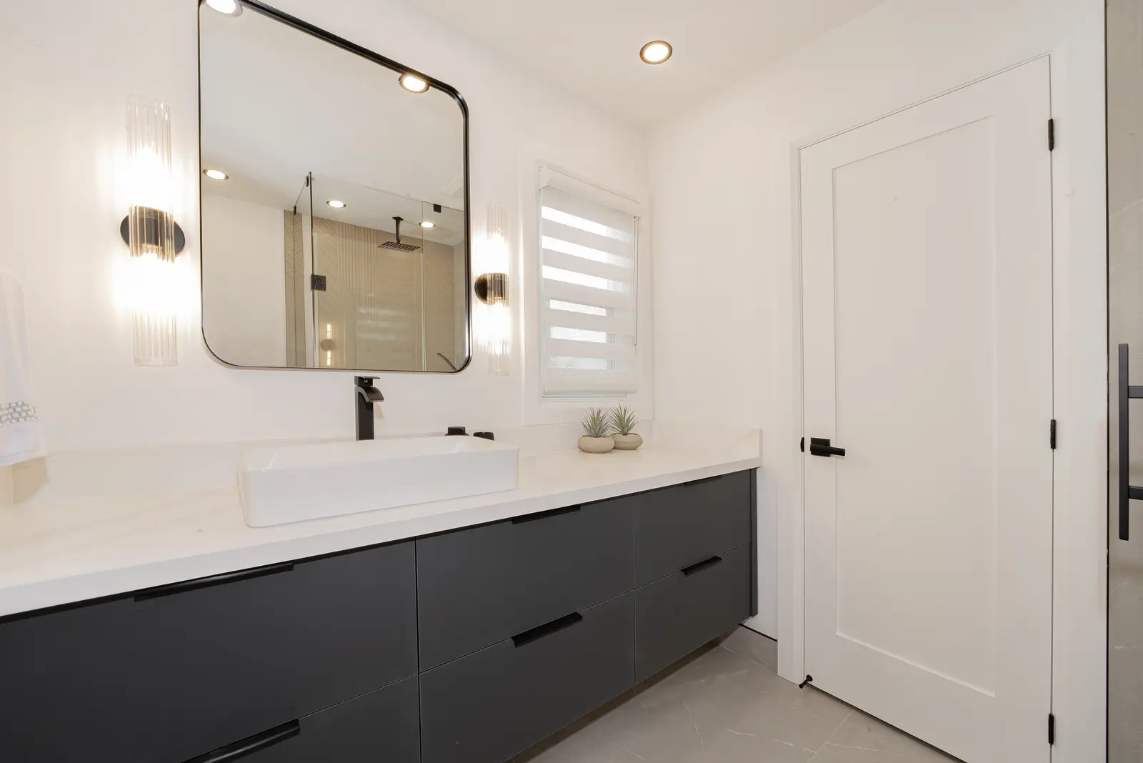 Interior of a Thornhill house renovation, with pale walls, a veined stone kitchen, light wood floors, and black fittings.