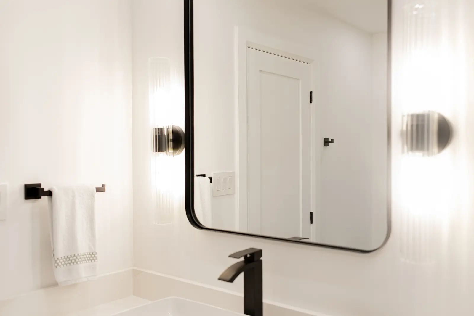 Interior of a Thornhill house renovation, with pale walls, a veined stone kitchen, light wood floors, and black fittings.