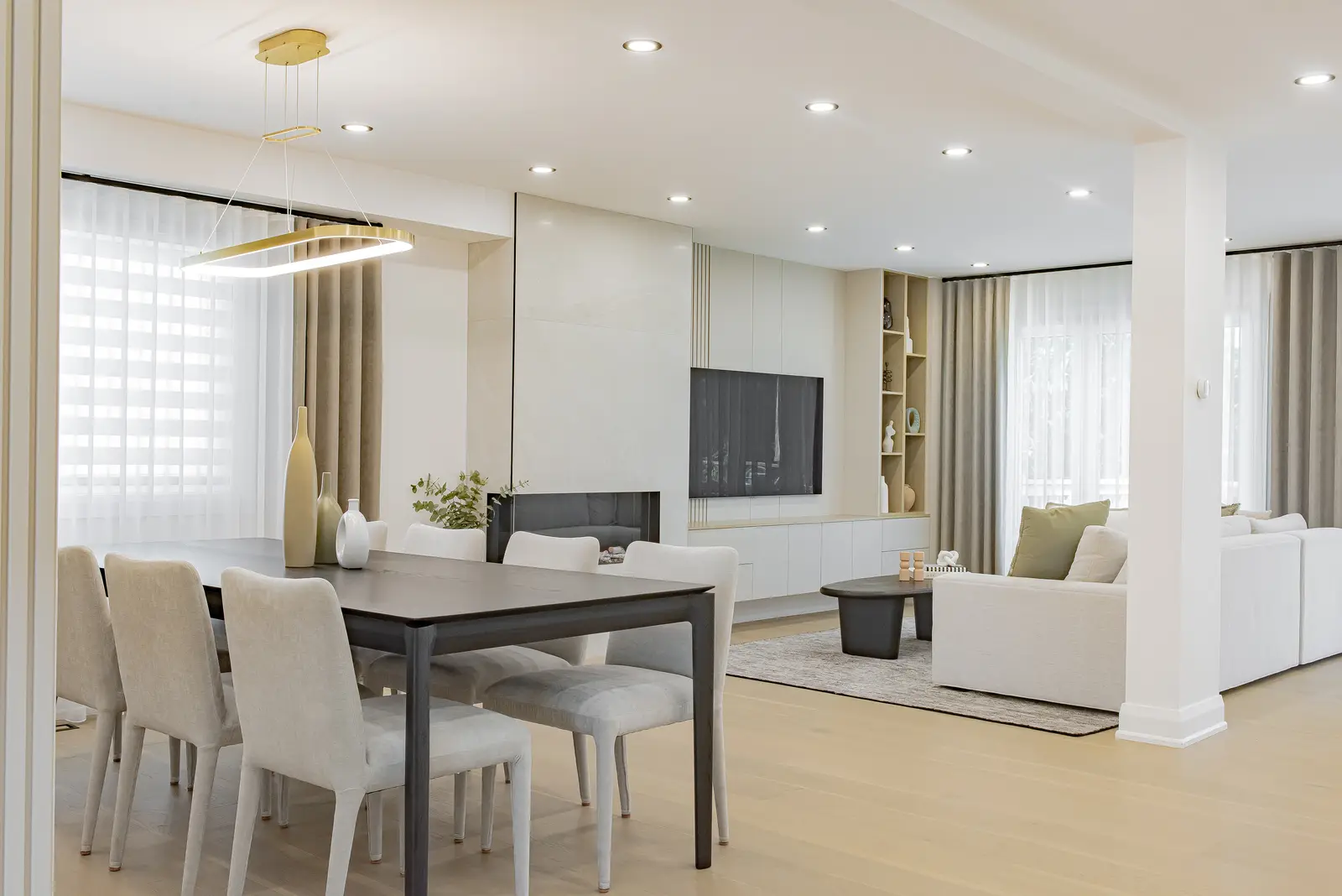 Interior of a Thornhill house renovation, with pale walls, a veined stone kitchen, light wood floors, and black fittings.