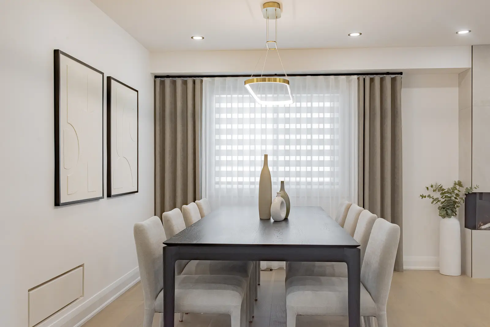 Interior of a Thornhill house renovation, with pale walls, a veined stone kitchen, light wood floors, and black fittings.