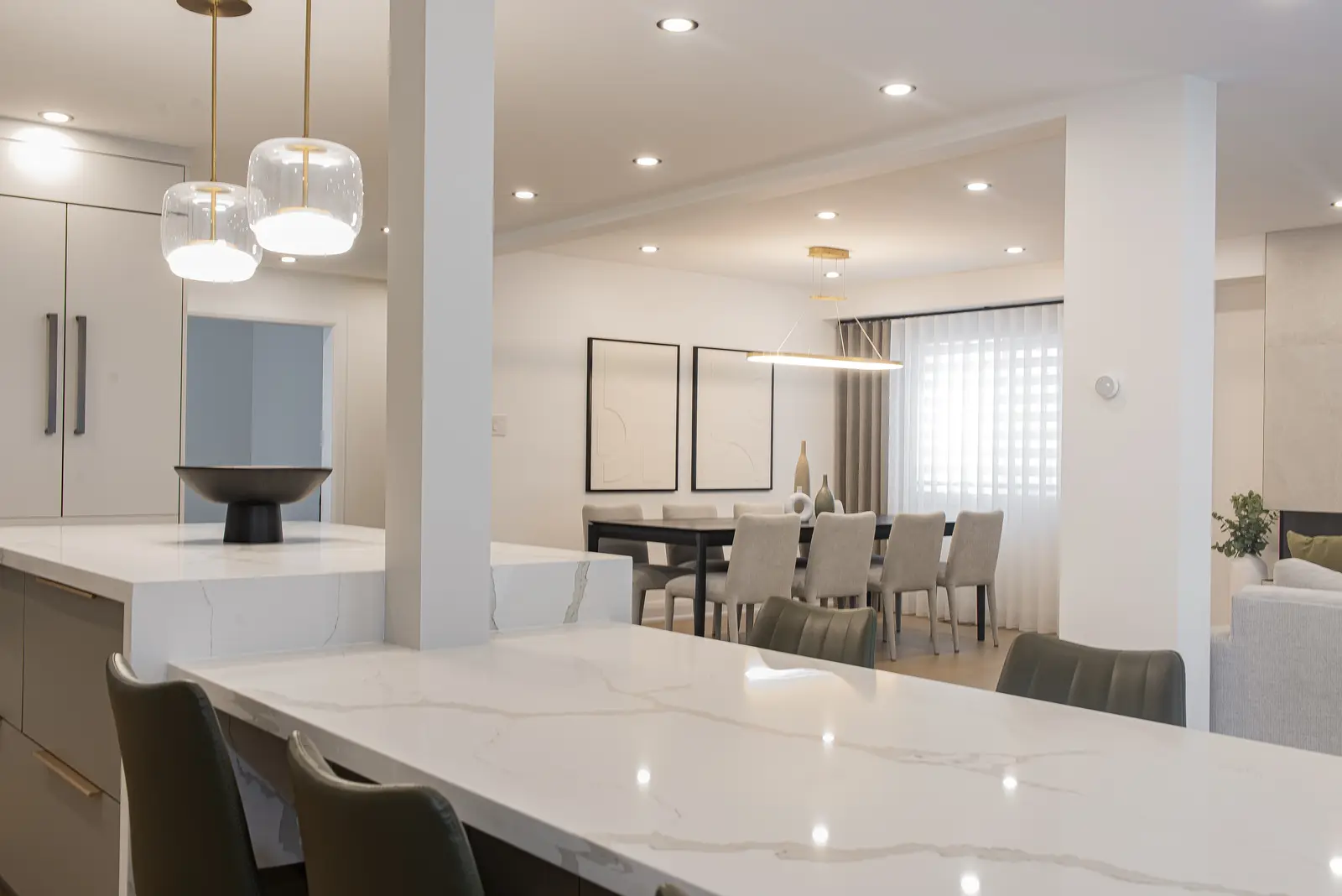 Interior of a Thornhill house renovation, with pale walls, a veined stone kitchen, light wood floors, and black fittings.
