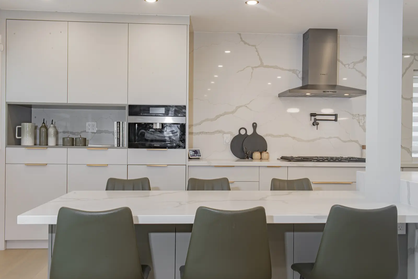 Interior of a Thornhill house renovation, with pale walls, a veined stone kitchen, light wood floors, and black fittings.