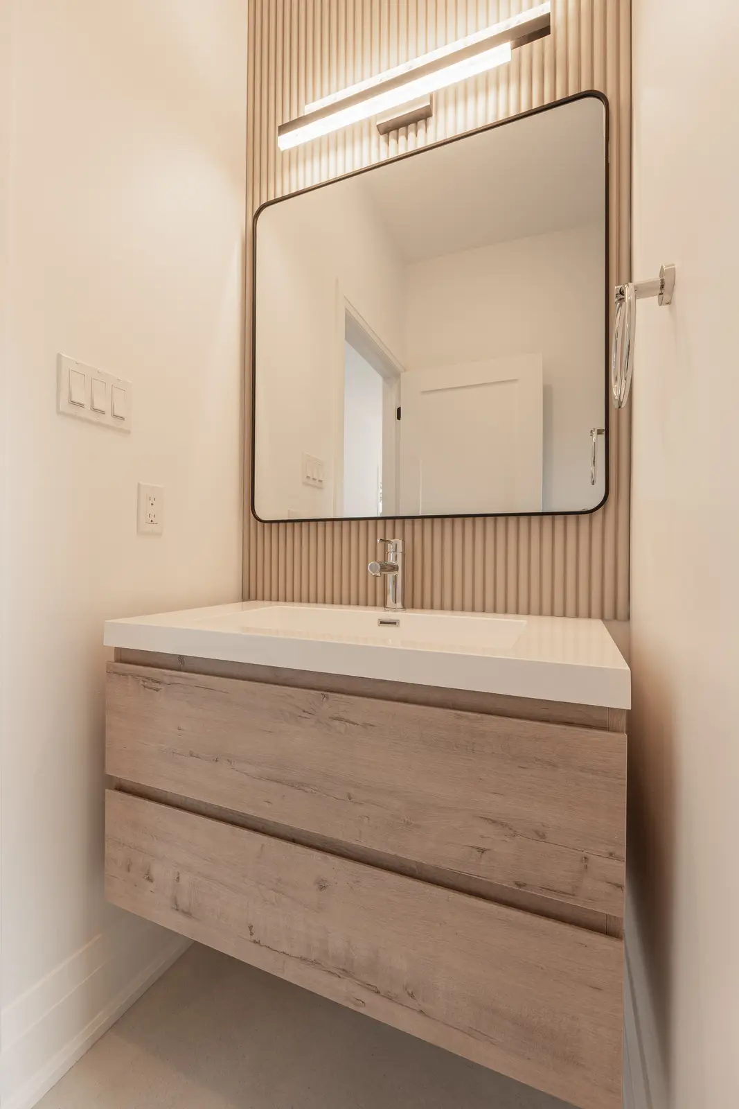 Room in a North York detached house renovation, with pale oak floors, white walls, and marble or warm wood millwork.